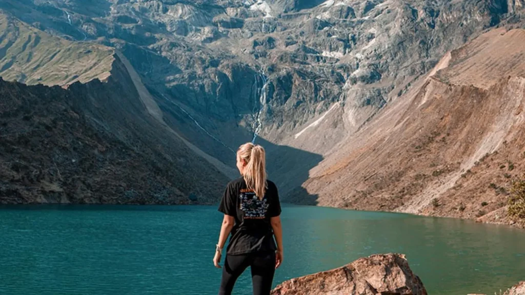 Turistas haciendo trekking en la Laguna Humantay de aguas turquesas cerca de Cusco.